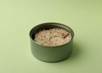 Tin with canned tuna on green background