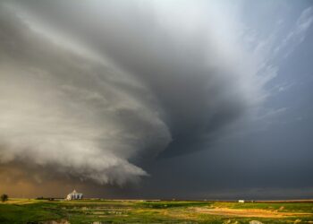 A tornado-producing supercell thunderstorm spinning over ranch land at sunset near Leoti, Kansas