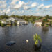 Flooded Florida street with stuck car after hurricane Debby rainfall surrounded with water. Consequences of natural disaster.