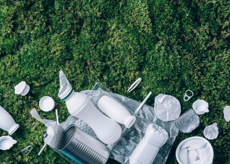 Food plastic packaging, trash on green moss background after picnic in forest. Top view. Copy space. Recycling plastic. Environmental pollution, ecology concept. Reuse garbage, recycle, plastic free